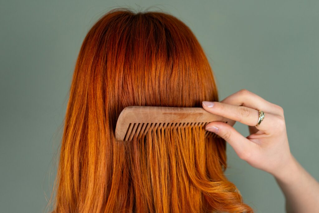 pexels photo 28994386 28994386 Close-up of a woman's red hair being combed with a wooden comb, capturing the smooth texture.